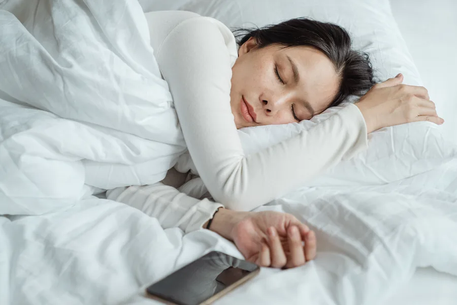 Someone asleep in bed with the phone set aside