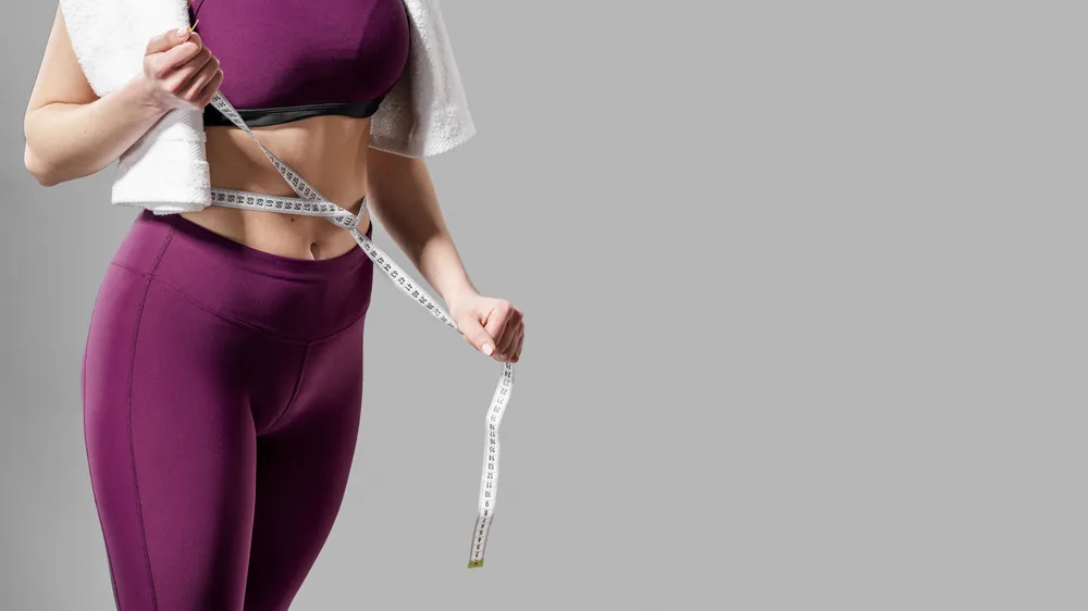 A measuring tape held around the waist at navel level